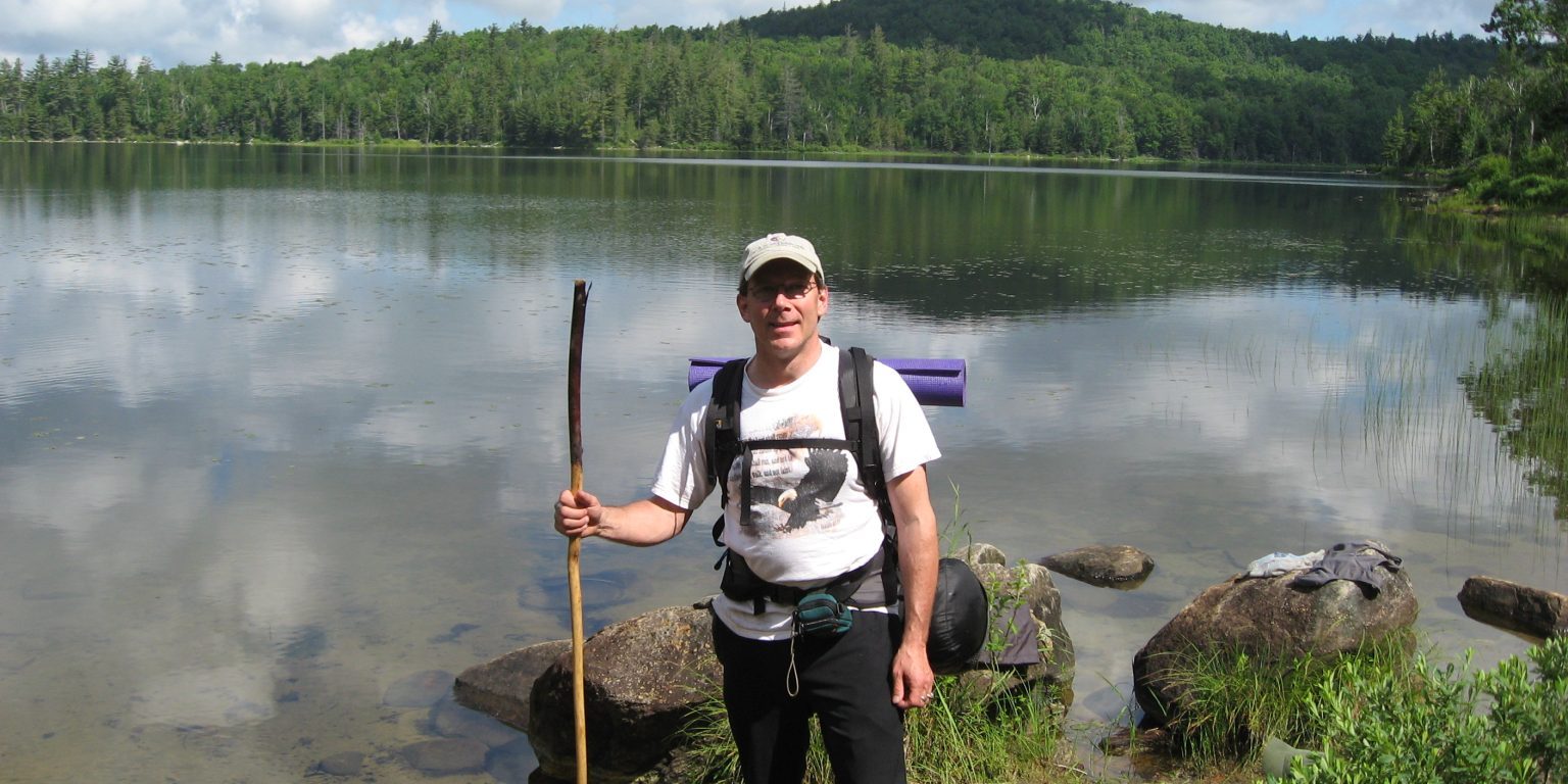 Hiker standing at the edge of a lake in the Adirondacks